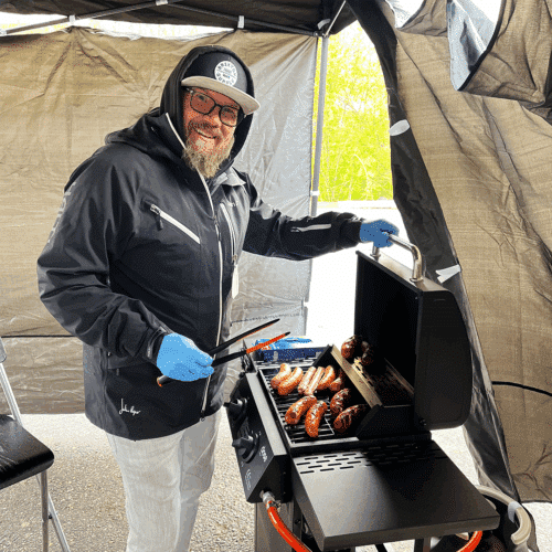 Mika Sopanen grillaa makkaraa telttakatoksessa.