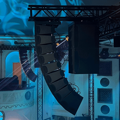 Adamson IS-sarjan line array -kaiuttimet profiilissa oikealta kuvattuna sinertävästi valaistussa Apollo Live Clubissa oikealta parvekkeelta kuvattuna, ja
