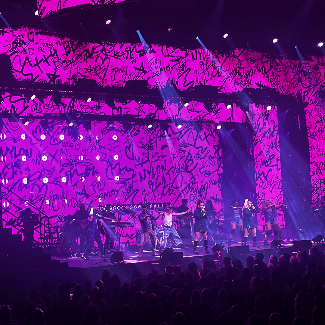 Nylon Beatin Jonna ja Erin lavalla mustissa asuissa Tytöt haluaa -konsertissa magentan värisen taustascreenin edessä.